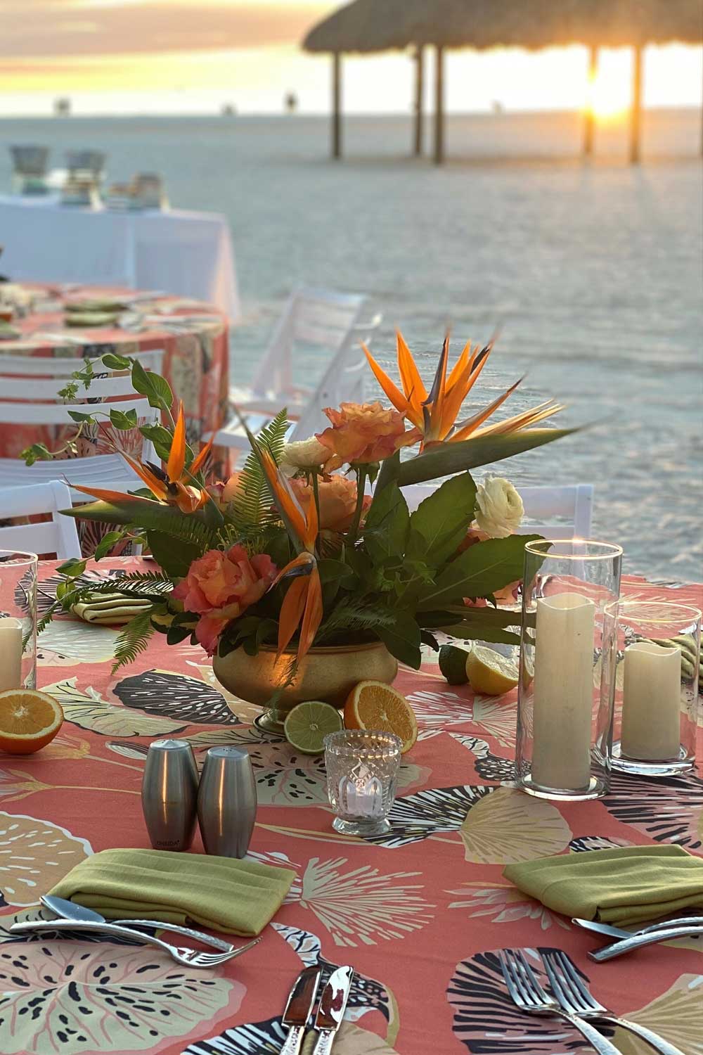 round table decorated with tropical flowers and citrus fruits on the beach